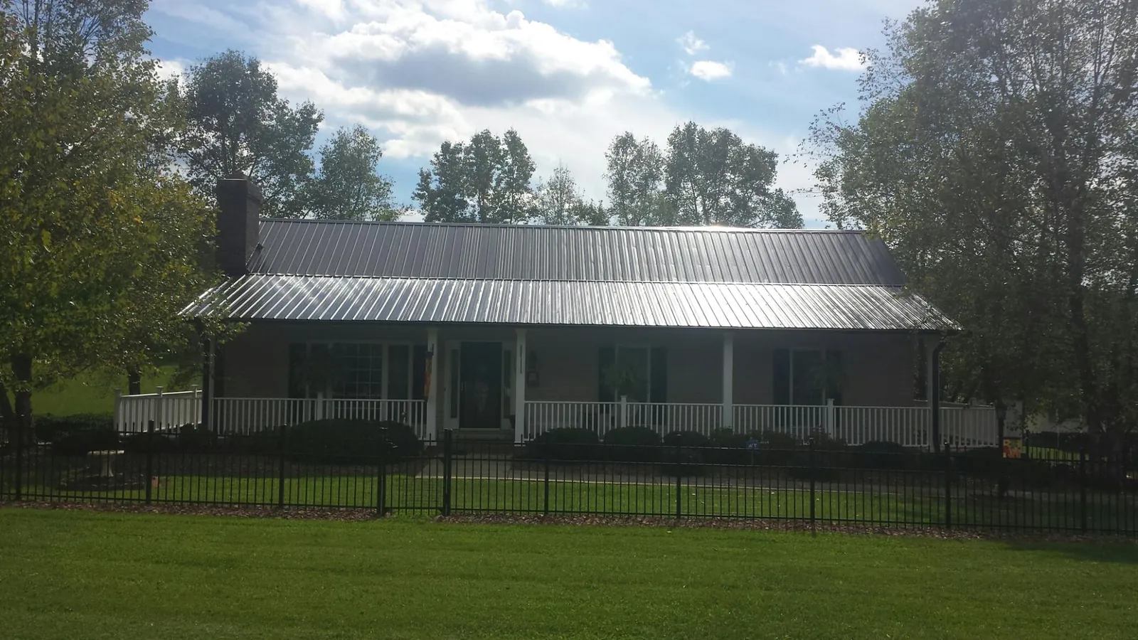 Gray metal roof on a brick ranch with a full width front porch — Gutter Guard Installation work by our crew in Moline