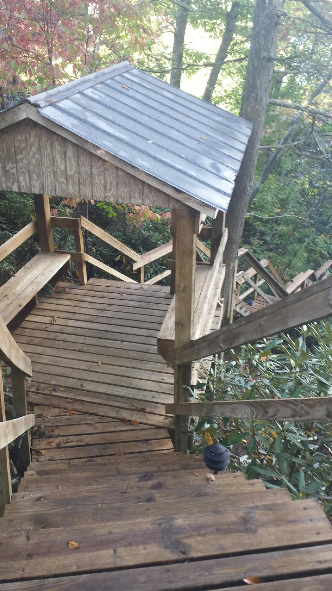 Metal roofed shelter over wooden steps on a wooded walkway — Skylight Repair & Installation work by our crew in Moline